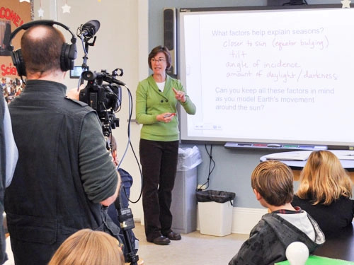 Teacher and students in a classroom being filmed by a film crew