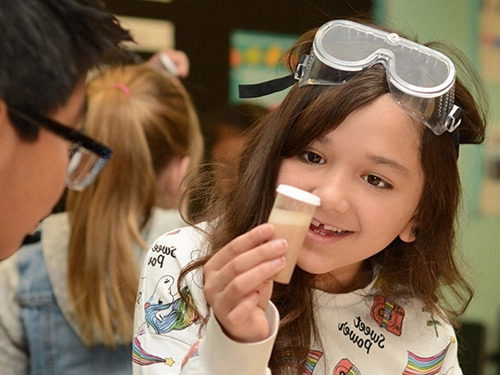 Elementary school student examining a sample of sand