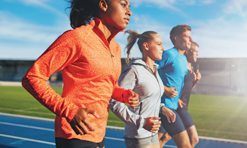 Four teenagers running on a track