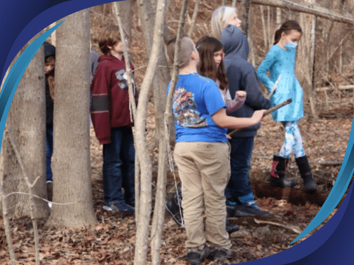 Science students in the woods with their teacher.