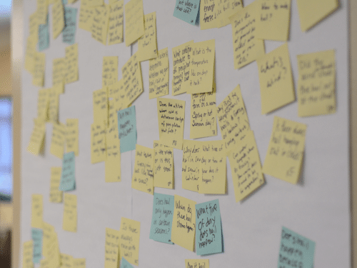 Wall covered with handwritten sticky notes used for brainstorming, planning, and organizing ideas.